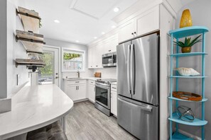 Una cocina moderna con armarios blancos, electrodomésticos de acero inoxidable y una unidad de estanterías azul.