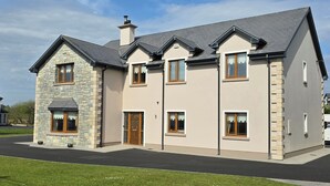 A two-story house with a stone facade, multiple windows, and a well-maintained lawn. - Irish Open 2026 - Sleeps 8 - 15 min from Doonbeg (Co Clare)