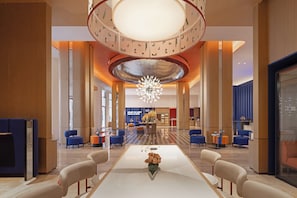 A spacious lobby with a central table, seating areas, and a distinctive ceiling design.