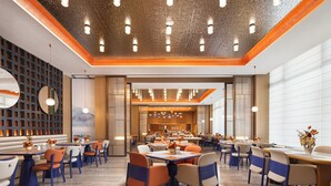 A spacious restaurant with multiple dining tables and chairs, a modern ceiling design, and a view into the dining area. - Hampton by Hilton Ningbo Xiangshan  (Ningbo)