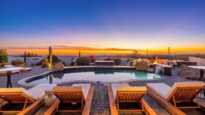 Un área de piscina en la azotea con sillones de descanso, un jacuzzi y una cascada.