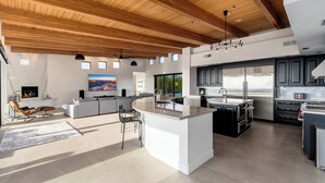 Una cocina moderna con una isla grande, electrodomésticos de acero inoxidable y techo de madera.