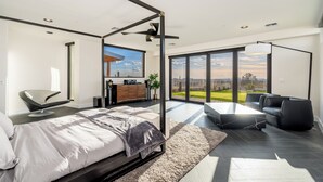 Un dormitorio moderno con una cama grande, un escritorio y vistas al exterior.