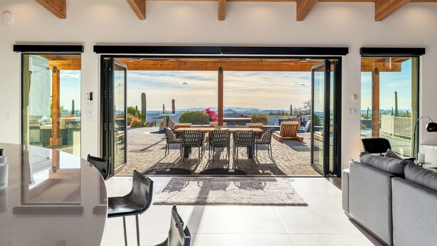 Un interior moderno con zona de comedor, sofá y vistas a través de puertas de vidrio.