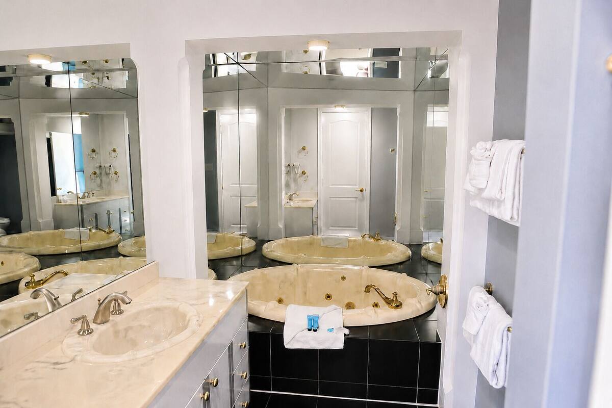 Un baño con tres lavamanos, una bañera y un espejo grande.