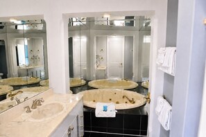 Un baño con tres lavamanos, una bañera y un espejo grande.