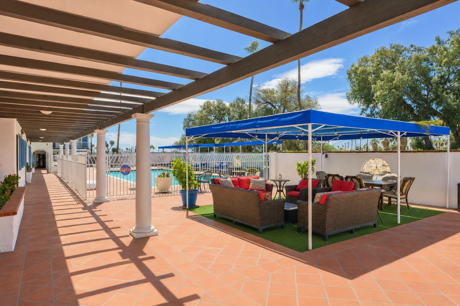 Un patio al aire libre con piscina, mobiliario cubierto y vista a la piscina.