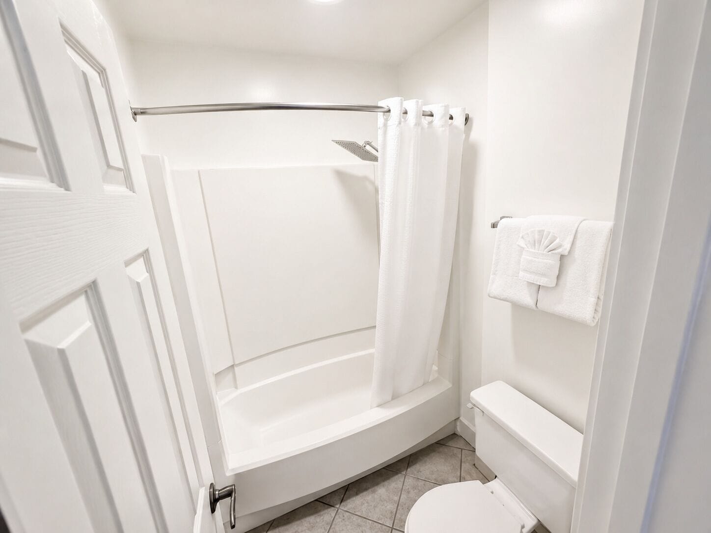 Un baño con bañera, inodoro, cortina de ducha y toallero.