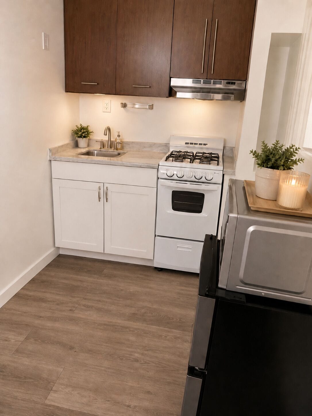 A kitchen with white cabinets, a stainless steel range, a built-in oven, a sink, and a microwave.