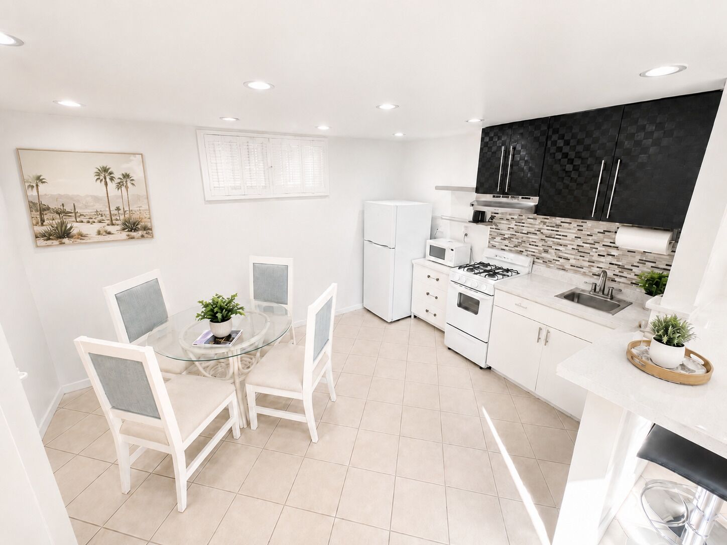 A compact kitchen with white appliances, a dining area with chairs, and a small table.