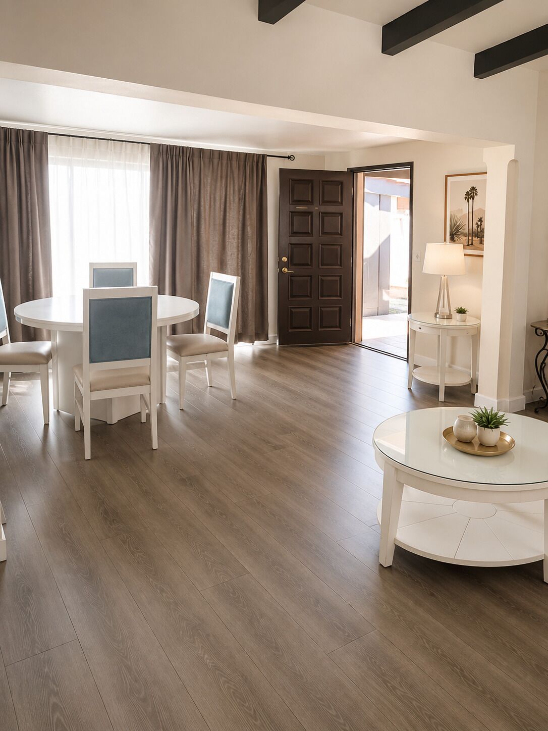 Habitación de hotel con comedor, puerta que da al exterior y una mesita de noche con lámpara y planta.