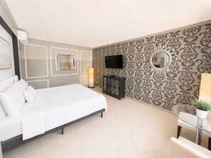 Habitación de hotel moderna con una cama, un televisor, un espejo y una pequeña mesa con una planta.