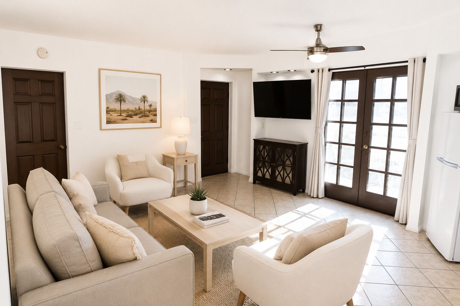 Una sala de estar con sofá, sillones, una mesa de centro, televisor y una puerta.
