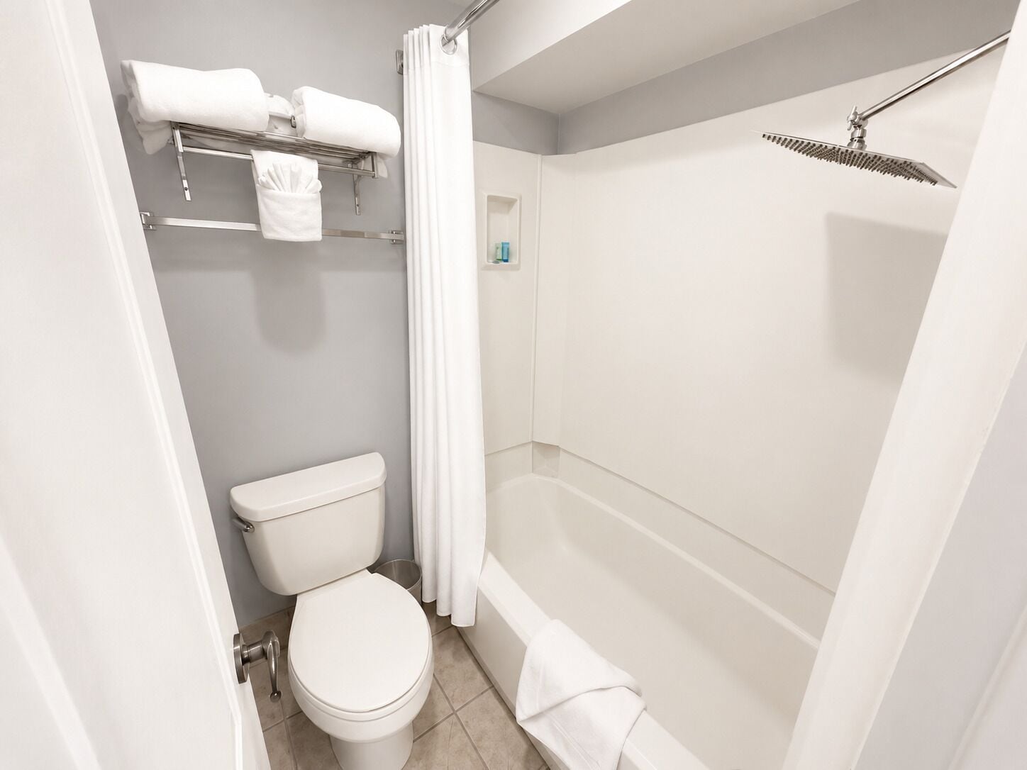 A bathroom with a toilet, a shower, and a towel rack.