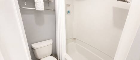 A bathroom with a toilet, a shower, and a towel rack.