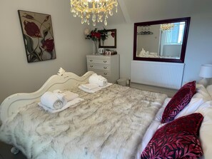 Ein Schlafzimmer mit Bett, Schminktisch, Spiegel und einer Deckenleuchte.