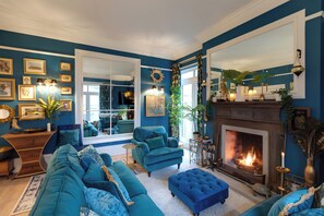 A living room with a fireplace, blue sofas, and a large mirror.