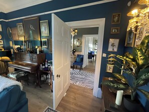 A room with a piano, a dining area, and a zebra-patterned rug.