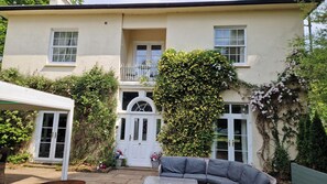 Une maison à deux étages, avec une façade blanche, un balcon et une porte d’entrée.
