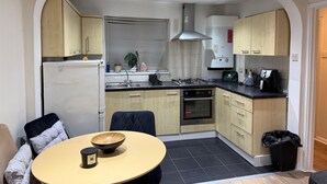A compact kitchen with a dining area, featuring a refrigerator, stove, sink, and cabinets.