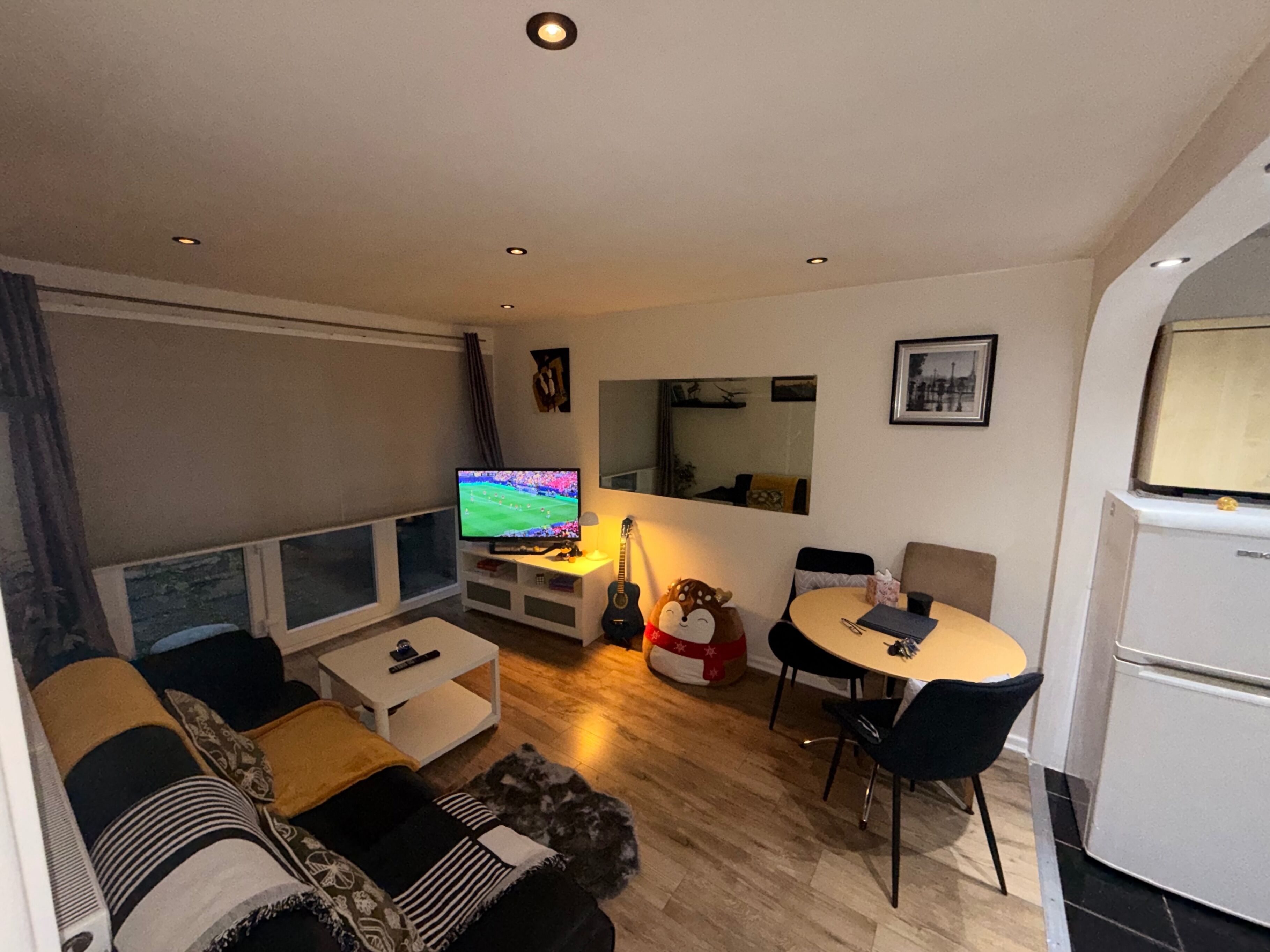 Una sala de estar con televisor, sofá, mesa de centro y un comedor con sillas y una mesa.
