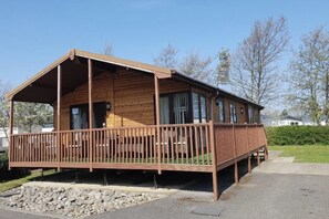 A wooden cabin with a porch, large windows, and a covered deck area.