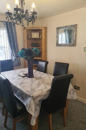 A dining area with a marble table, black chairs, a chandelier, a wooden bookshelf, and a mirror on the wall. - Wooden Lodge, Sleeps 9 with Veranda & Decking (Fleetwood)