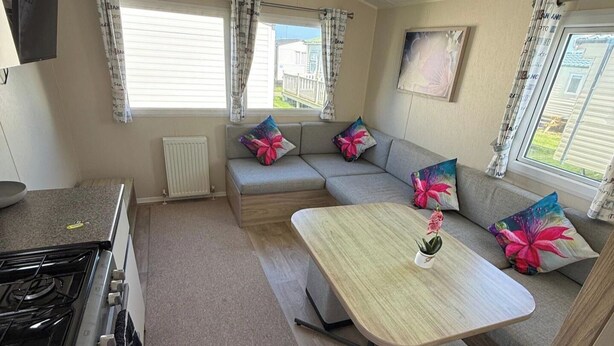 A compact living space with a kitchenette, a sofa set, and a dining table. - Seaside Caravan Sleeps 7 - Pet Friendly, Garden (Rhyl)