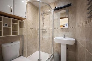 Une salle de bain moderne avec une douche à parois de verre, un lavabo blanc et des toilettes.