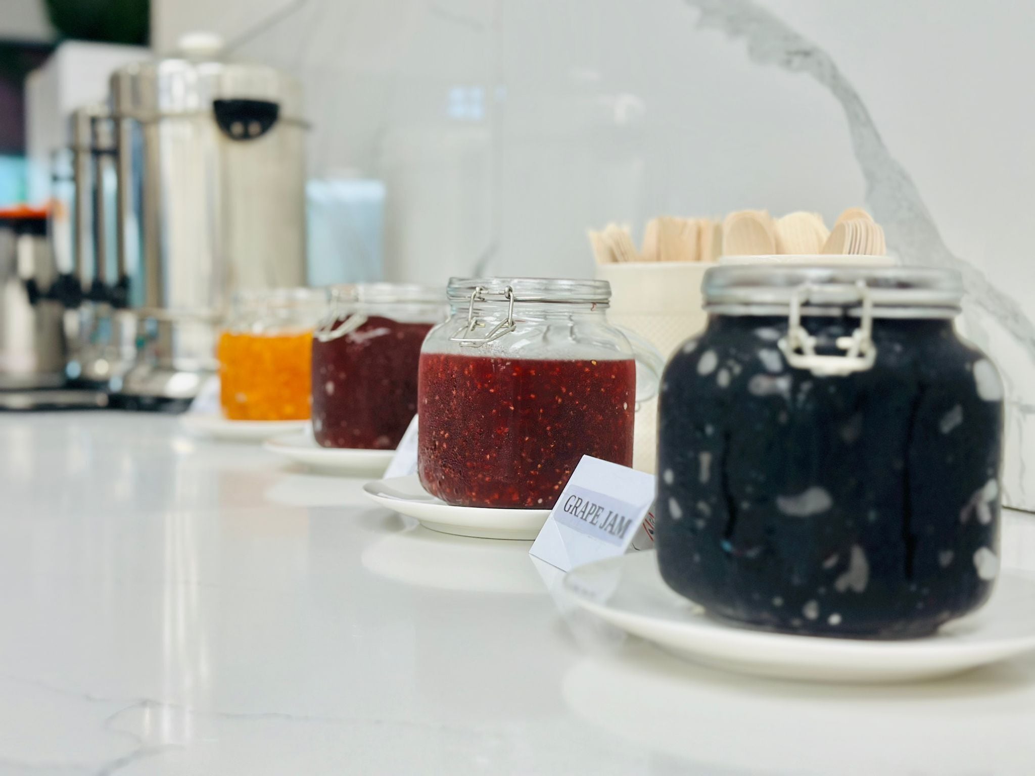 A display of various jams on plates with labels.