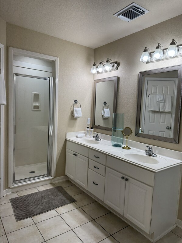 Une salle de bain équipée d’une douche, d’un lavabo, d’un miroir et d’un porte-serviettes.