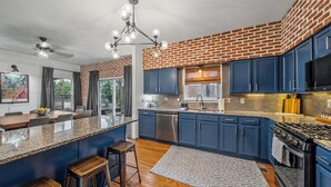 A kitchen with blue cabinets, a granite countertop, a stainless steel dishwasher, and a black stove. - Hot Tub, Games, Gated Parking near SLU & Downtown (St. Louis)