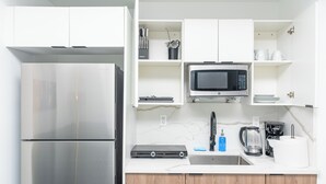 A modern kitchen with a stainless steel refrigerator, a microwave, a coffee maker, and wooden cabinets. - Central 1BR in Miami Near Wynwood and Marlins Park (Miami)