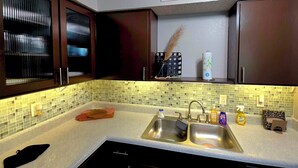 Uma cozinha moderna com pia dupla, eletrodomésticos de aço inoxidável e painel de azulejos.