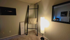 Quarto com escada, luminária na parede e espelho refletindo uma pessoa.