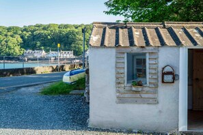 Un petit bâtiment rustique, doté d’un toit en pente, d’une porte en bois et d’une fenêtre au-dessus de laquelle est accrochée une enseigne.
