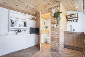 Une cuisine moderne avec des murs en bois, un téléviseur encastré et un motif de parquet en chevrons.