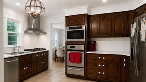 Une cuisine moderne avec des meubles en bois foncé, des appareils électroménagers en acier inoxydable et un sol carrelé.