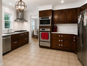 A modern kitchen with dark wooden cabinets, stainless steel appliances, and a tiled floor.