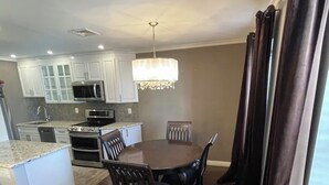 A modern kitchen with white cabinets, a microwave, and a chandelier. - Fabulous condo with AC in the heart of Clifton, 8 mins to Giant’s Stadium (Clifton)