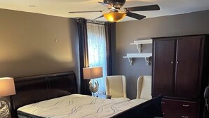 A bedroom with a bed, bedside table, lamp, chair, and a ceiling fan. - Fabulous condo with AC in the heart of Clifton, 8 mins to Giant’s Stadium (Clifton)