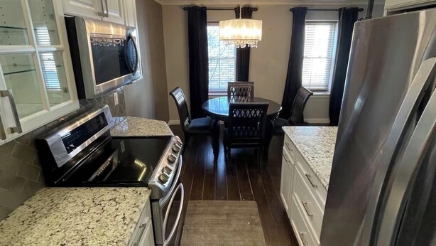 A kitchen with a granite countertop, stainless steel appliances, a dining table with chairs, and a chandelier. - Fabulous condo with AC in the heart of Clifton, 8 mins to Giant’s Stadium (Clifton)