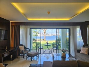 Uma sala de estar moderna com uma grande porta de correr de vidro que dá para uma varanda com vista para o mar.