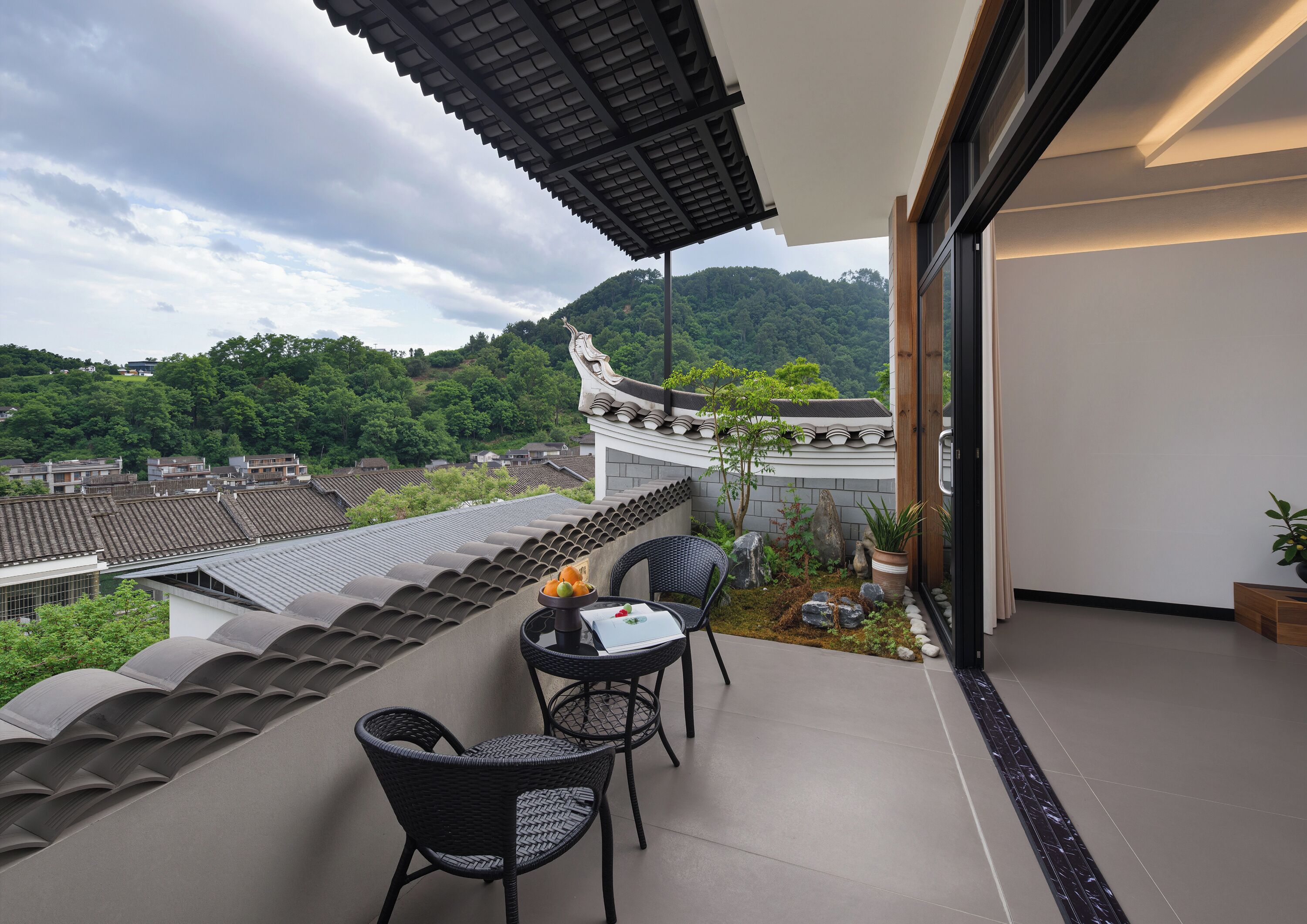 Un balcon agrémenté de chaises de style traditionnel, une table avec des fruits et une vue sur un paysage montagneux.