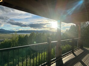 Ett trädäck med ett räcke som vetter ut mot ett landskap med berg och en sjö eller ett annat vattendrag.