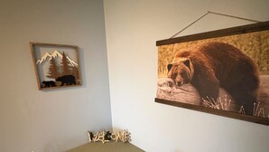 Un'area pranzo con un tavolo e sedie, un quadro con un orso e un quadro più piccolo con una veduta montana.