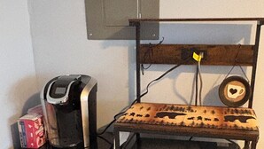 Una cucina compatta con macchina del caffè, forno a microonde e piccolo frigorifero.