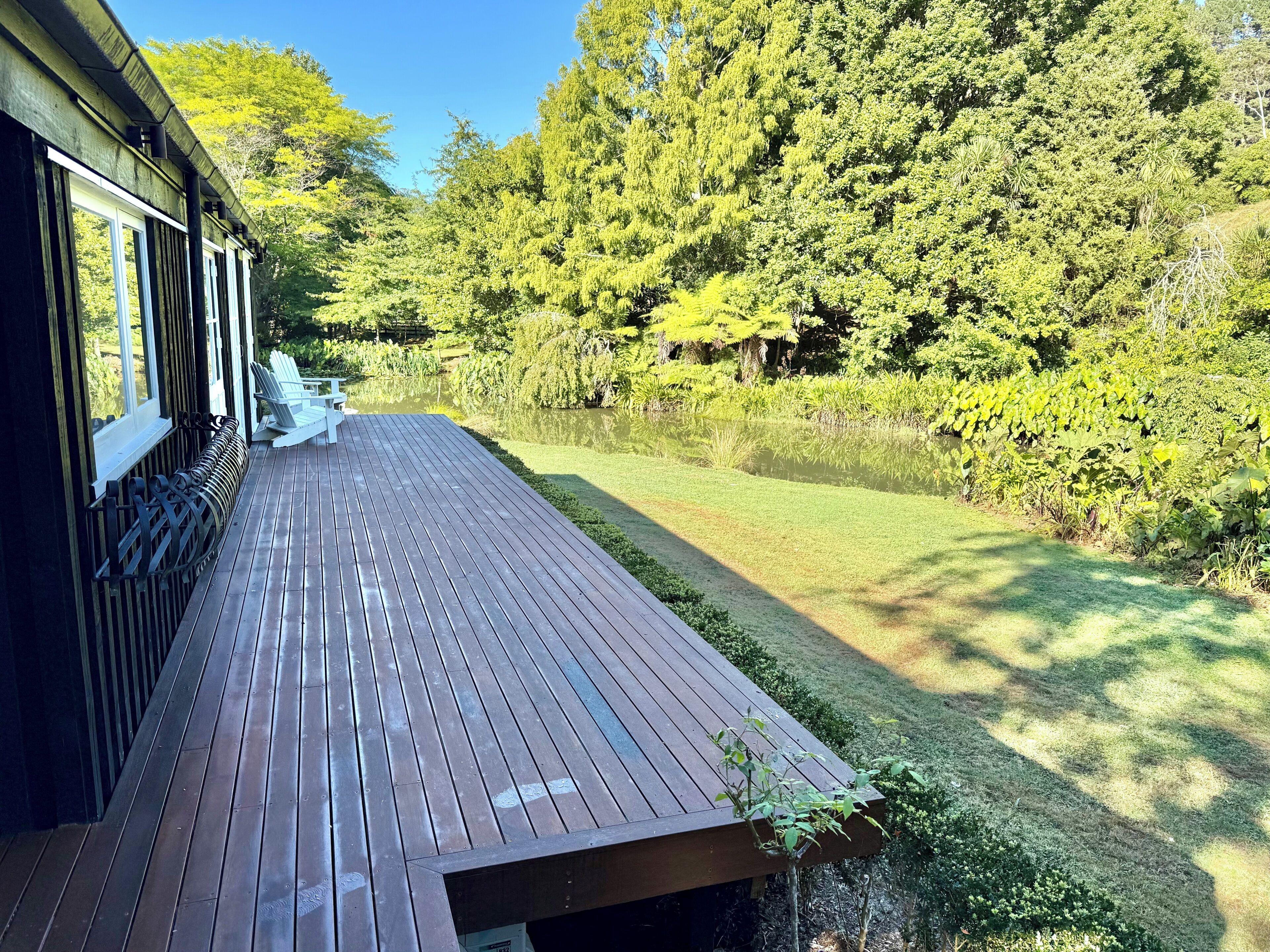 A wooden deck with a bench, surrounded by lush greenery and trees.