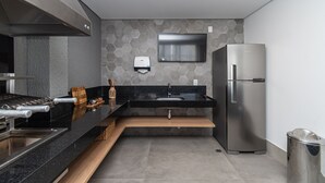A modern kitchen with a stainless steel refrigerator, a built-in oven, and a microwave. - Pause Living - Nex One Paraíso (São Paulo)