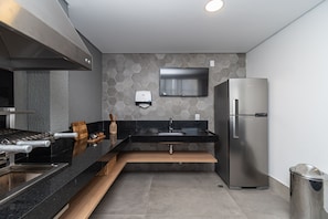 A modern kitchen with a stainless steel refrigerator, a built-in oven, and a microwave. - Pause Living - Nex One Paraíso (São Paulo)